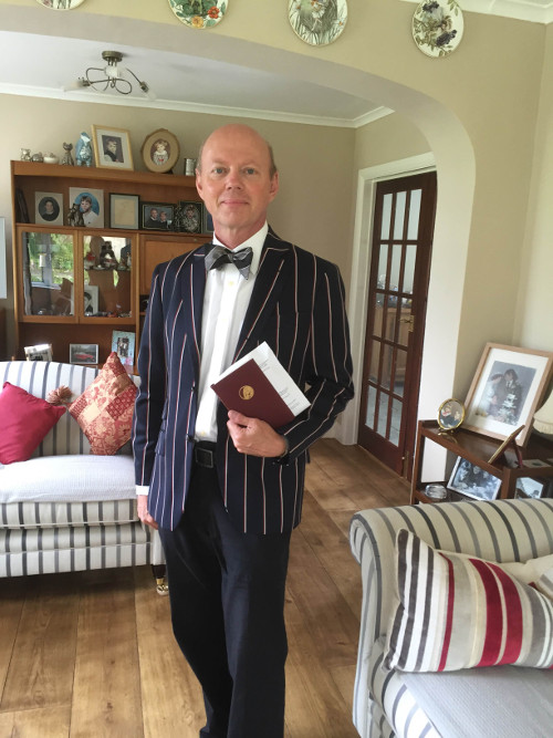 Man wearing jacket and bow tie holding a book in formal sitting room